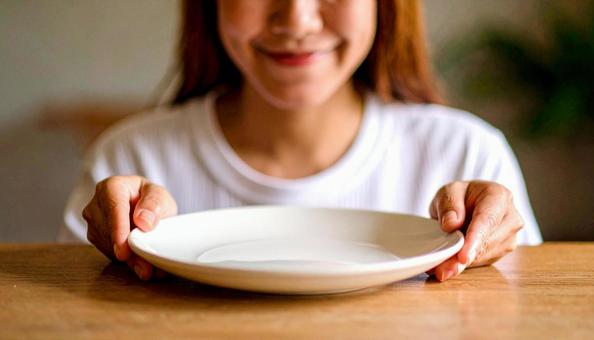 食後、空になったお皿を前に笑顔の女性 食後、空になったお皿を前に笑顔の女性の写真