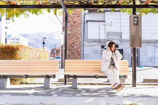 ベンチに座ってイヤホンで音楽を聴く女性 女性,イヤホン,音楽の写真素材