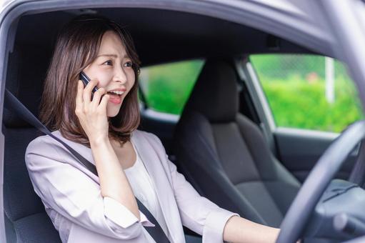 スマホを使いながら車を運転する女性 スマホを使いながら車を運転する女性 白バック,道,交通法の写真素材