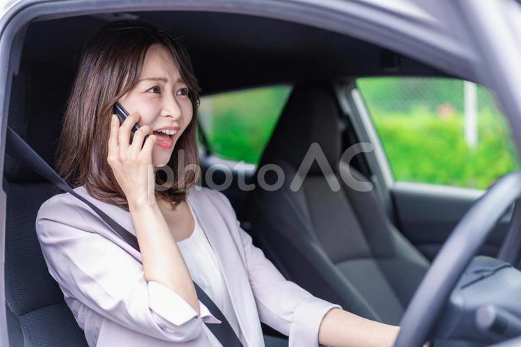 スマホを使いながら車を運転する女性 白バック,道,交通法の写真素材