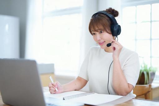 ペンを持ち笑顔でパソコンを見つめる女性 女性,ヘッドセット,ルーズリーフの写真素材