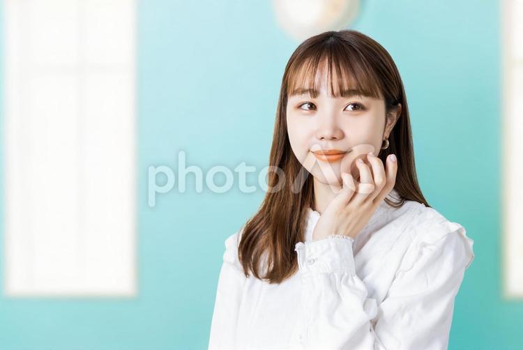 頬に手を当てて微笑む若い女性 女性,笑顔,若いの写真素材