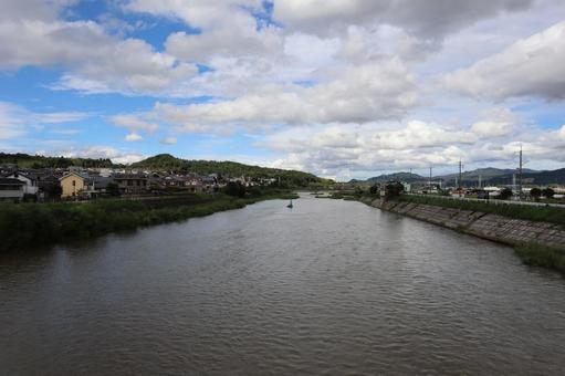 増水した川と町と山と雲と青空の風景 増水した川と町と山と雲と青空の風景の写真