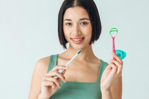歯ブラシやフロスなどを持っている女性 歯ブラシやフロスなどを持っている女性の写真