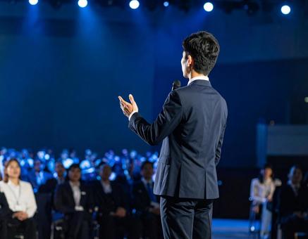 ステージ上で堂々とプレゼンする男性 ステージ上で堂々とプレゼンする男性の写真