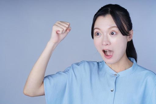 青い服の女性が拳を上げて元気なポーズ 女性,ガッツポーズ,口を開けるの写真素材