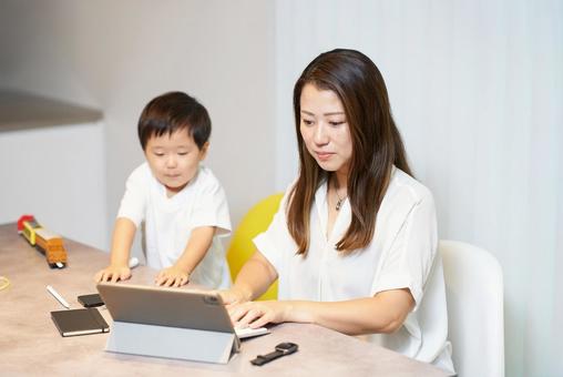 リモート中の母親の横で遊ぶ子供 リモート中の母親の横で遊ぶ子供 女性,リモートワーク,子育ての写真素材