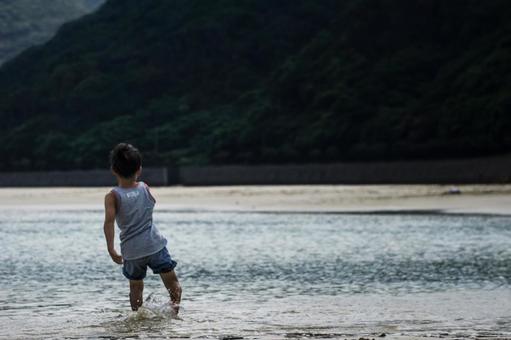 <素材>夕暮れの海で水遊びをする男の子 <素材>夕暮れの海で水遊びをする男の子の写真