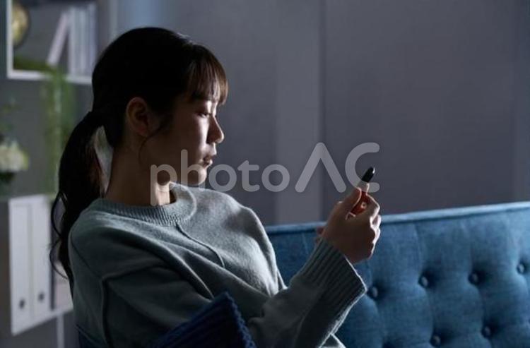 スマートフォンを見て落ち込む女性 女性,落ち込む,スマートフォンの写真素材
