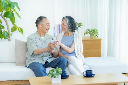 リビングでスマホを見るシニア夫婦 リビングでスマホを見るシニア夫婦 スマホ,シニア,笑顔の写真素材