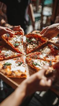友人と囲む食卓でピザを取り分ける手 友人と囲む食卓でピザを取り分ける手の写真