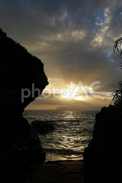 岩のシルエットの隙間から見える夕陽 夕焼け,夕陽,沖縄の写真素材