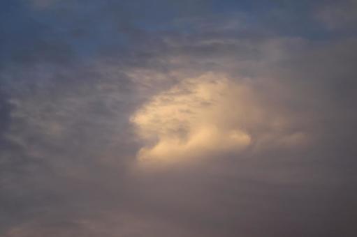 雲の多い色づく夕空の写真