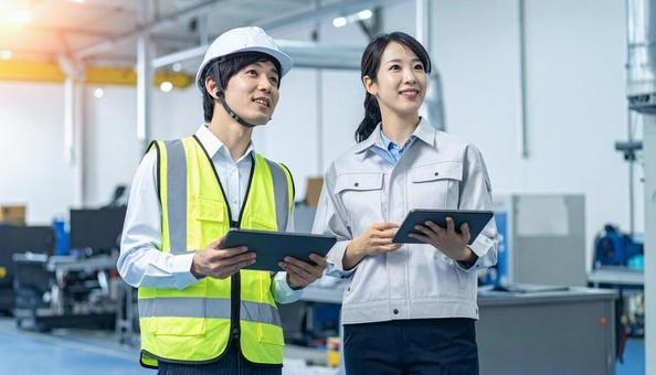 工場でタブレットで製品を検査する作業員 工場でタブレットで製品を検査する作業員の写真