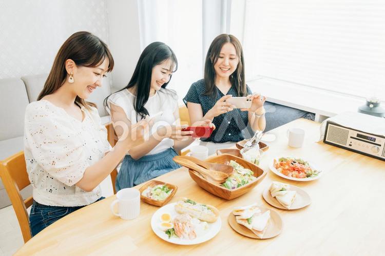 家でパーティーする女性（スマホ・撮影） 女子会,スマホ,スマートフォンの写真素材
