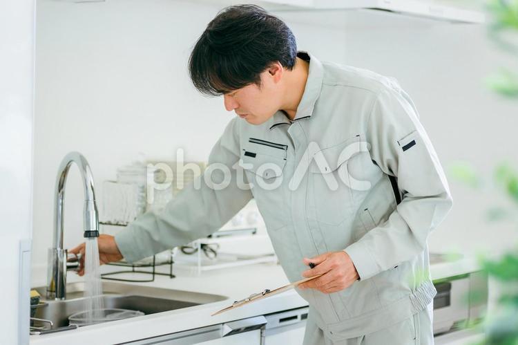 キッチンと作業着姿の男性（水道） 水道屋,水漏れ,漏水の写真素材
