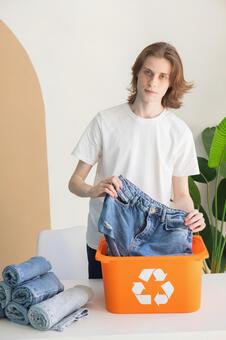 リサイクルボックスにデニムを入れる外国人の男性 男性,リサイクル,真剣の写真素材