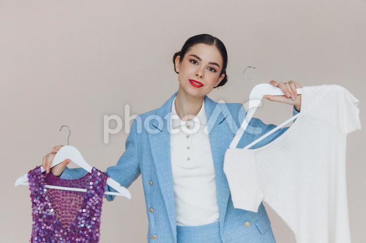 トップスを持って微笑むスーツの女性 女性,水色,持つの写真素材