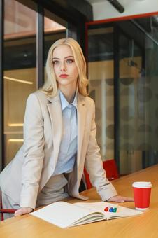 テーブルに手をついて立っているビジネスウーマンの写真