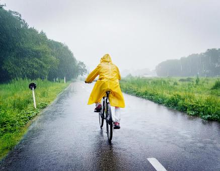 レインコートを着て自転車に乗る女性 レインコートを着て自転車に乗る女性の写真