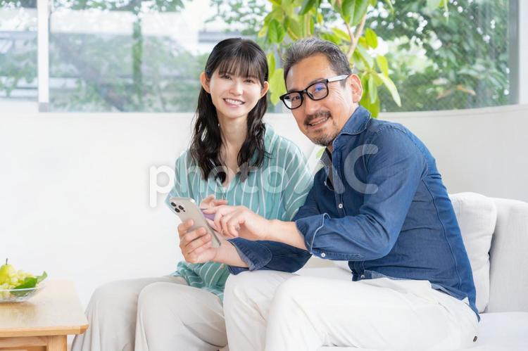 リビングでスマホを見るミドルの夫婦 夫婦,家族,ミドルの写真素材