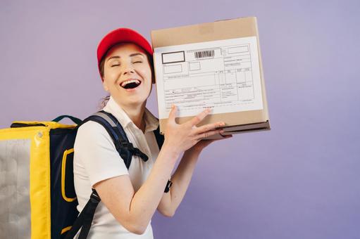 段ボール箱を持つ笑顔の配達員の女性 配達,フードデリバリー,デリバリーの写真素材