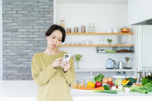 キッチンでスマホを使うミドルの女性 キッチンでスマホを使うミドルの女性 スマートフォン,キッチン,台所の写真素材
