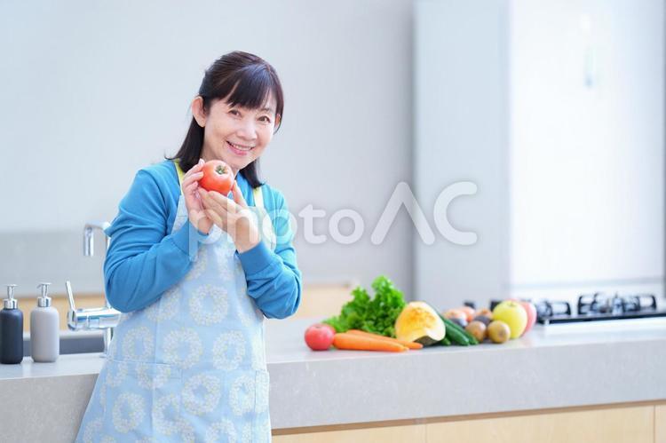 トマトを手に微笑む中年女性 主婦,家政婦,エプロンの写真素材