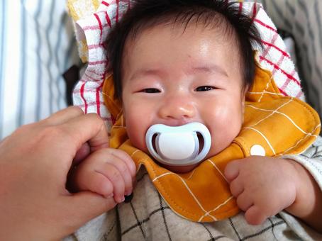 ママの手とおしゃぶりでご機嫌な赤ちゃん ママの手とおしゃぶりでご機嫌な赤ちゃんの写真