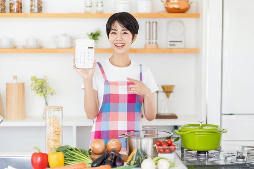 キッチンで電卓を持つ主婦。 キッチンで電卓を持つ主婦。の写真