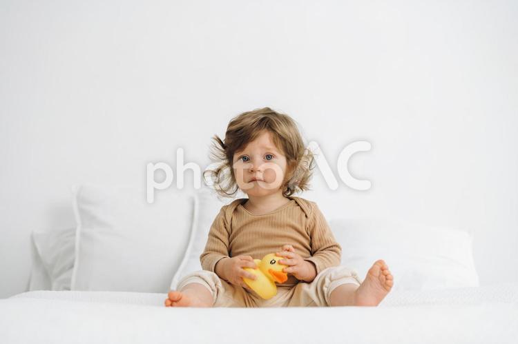 カメラ目線で黄色い玩具を持ち座る赤ちゃん 赤ちゃん,かわいい,お座りの写真素材