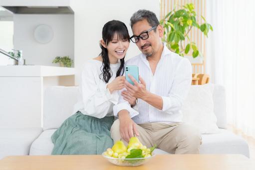 リビングでスマホを見るミドルの夫婦 夫婦,家族,ミドルの写真素材