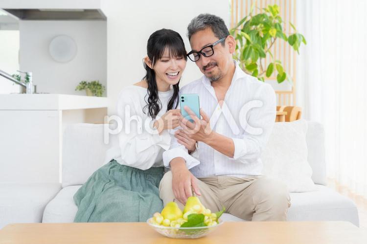 リビングでスマホを見るミドルの夫婦 夫婦,家族,ミドルの写真素材