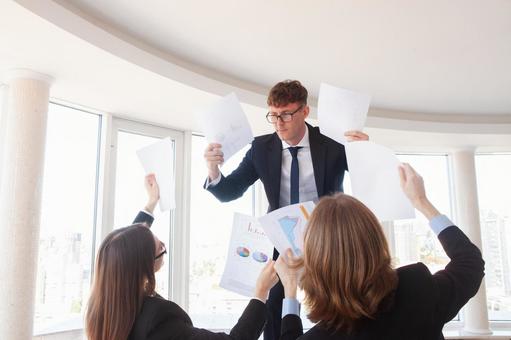 両手に書類を持つ男性に書類を見せる2人 男性,男女,外国人の写真素材