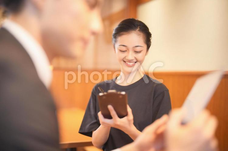 男性客から注文を取る女性店員（横） 女性,男女,大学生の写真素材