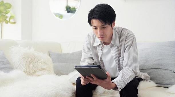 深刻な表情でニュースをみるアジア人男性 深刻な表情でニュースをみるアジア人男性 男性,ニュース,タブレットの写真素材