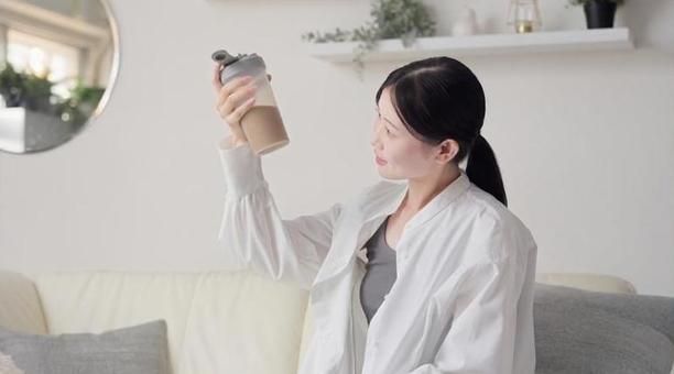 リビングでプロテインを見るアジア人女性 プロテイン,見る,女性の写真素材
