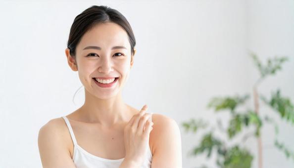 明るい室内でスキンケアをする笑顔の女性 明るい室内でスキンケアをする笑顔の女性の写真