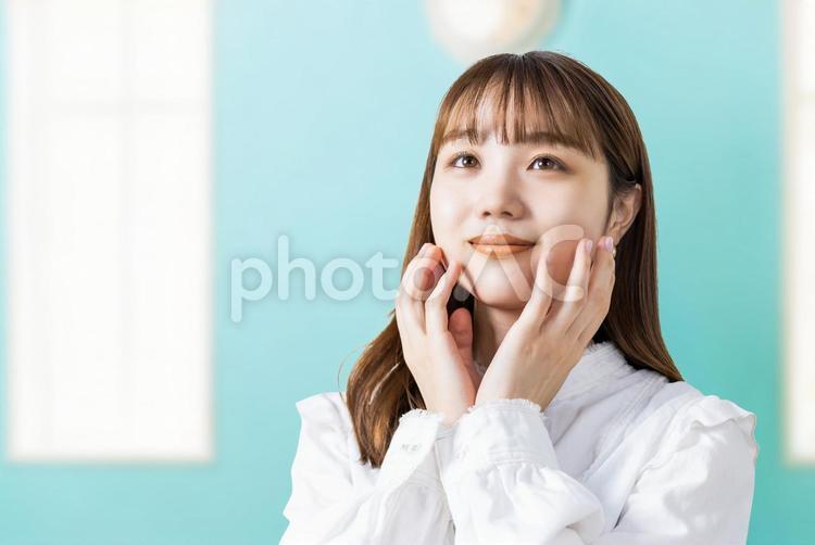 両手で頬を押さえて微笑む若い女性 女性,ビジネス,笑顔の写真素材