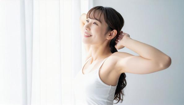 起床時にカーテンの前で朝日を浴びる女性 起床時にカーテンの前で朝日を浴びる女性の写真