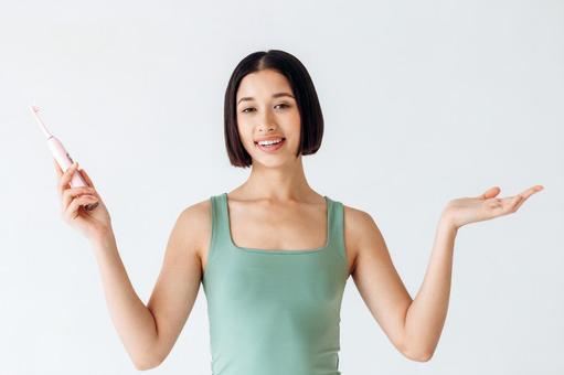 電動歯ブラシを持って話す女性 電動歯ブラシを持って話す女性 女性,歯ブラシ,電動の写真素材