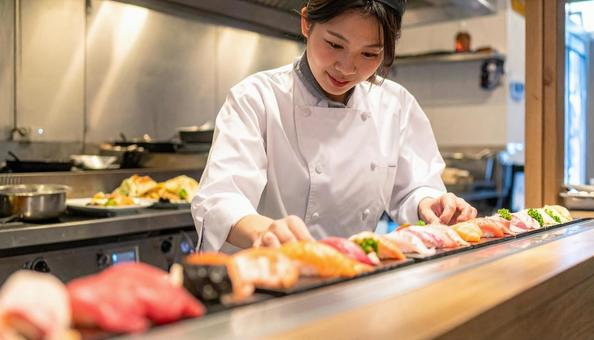 レストランの調理場で料理するスタッフ女性 レストランの調理場で料理するスタッフ女性の写真