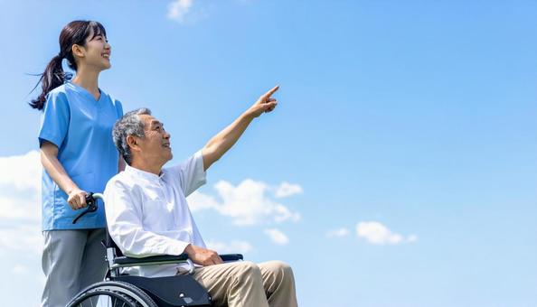 青空の下 同方向を見るシニア男性と介護士 青空の下 同方向を見るシニア男性と介護士の写真