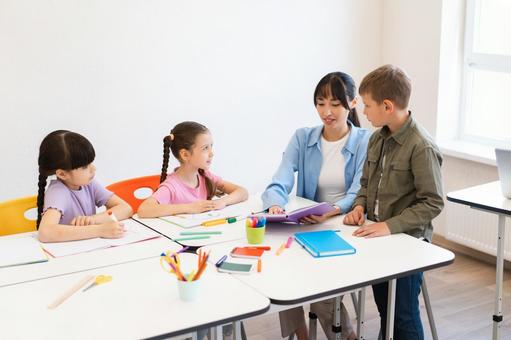 座ってノートを見せる先生 女性,女の子,男の子の写真素材