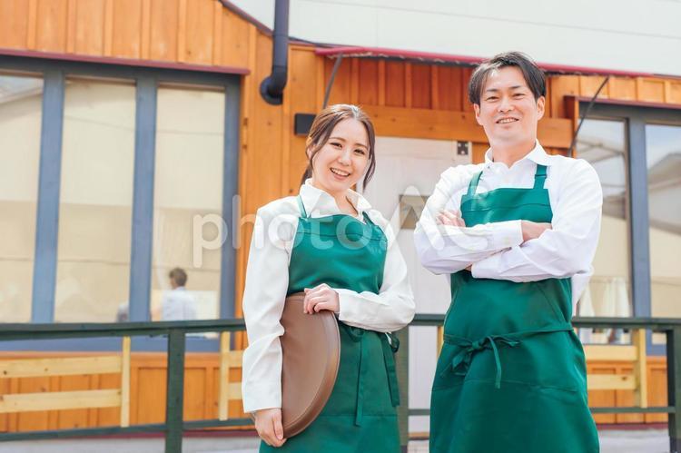 お店の前に立つエプロン姿の男女 カフェ,飲食店,ウェイトレスの写真素材