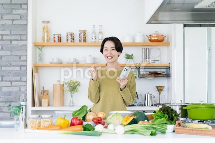 キッチンで頑張る主婦 ガッツポーズ,スマホ,キッチンの写真素材