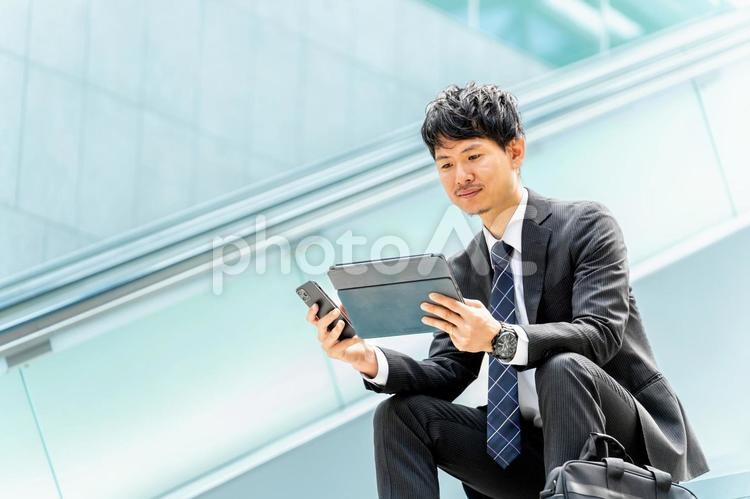 スマホとタブレットを使う男性ビジネスマン 男性,ビジネス,ビジネスマンの写真素材