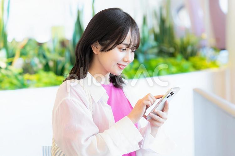 スマホを見る笑顔の女性 スマホ,若い女性,笑顔の写真素材