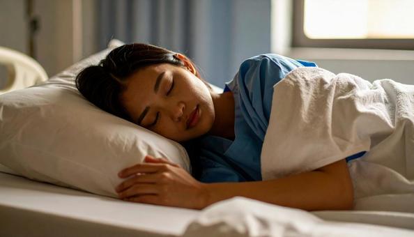 片腕の下にバスタオルを置いて眠る女性患者 片腕の下にバスタオルを置いて眠る女性患者の写真