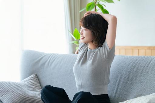 ソファに座ってストレッチをする女性 ソファに座ってストレッチをする女性 女性,ソファ,微笑むの写真素材